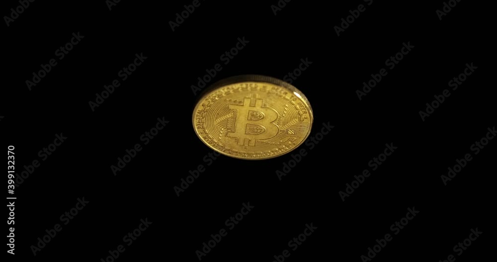 A gold bitcoin coin rotates against a dark background and increases in the frame. A gold bitcoin coin rotates against a dark background and increases in the frame.