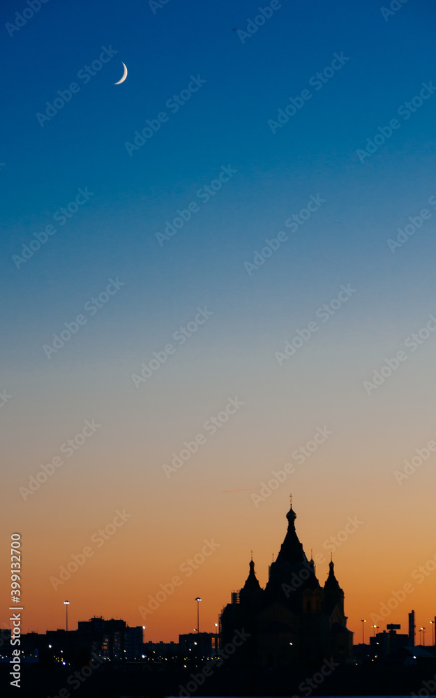 Fototapeta premium silhouette of the church on the background of sunset, in the sky a crescent