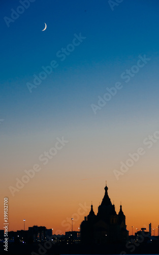 silhouette of the church on the background of sunset, in the sky a crescent