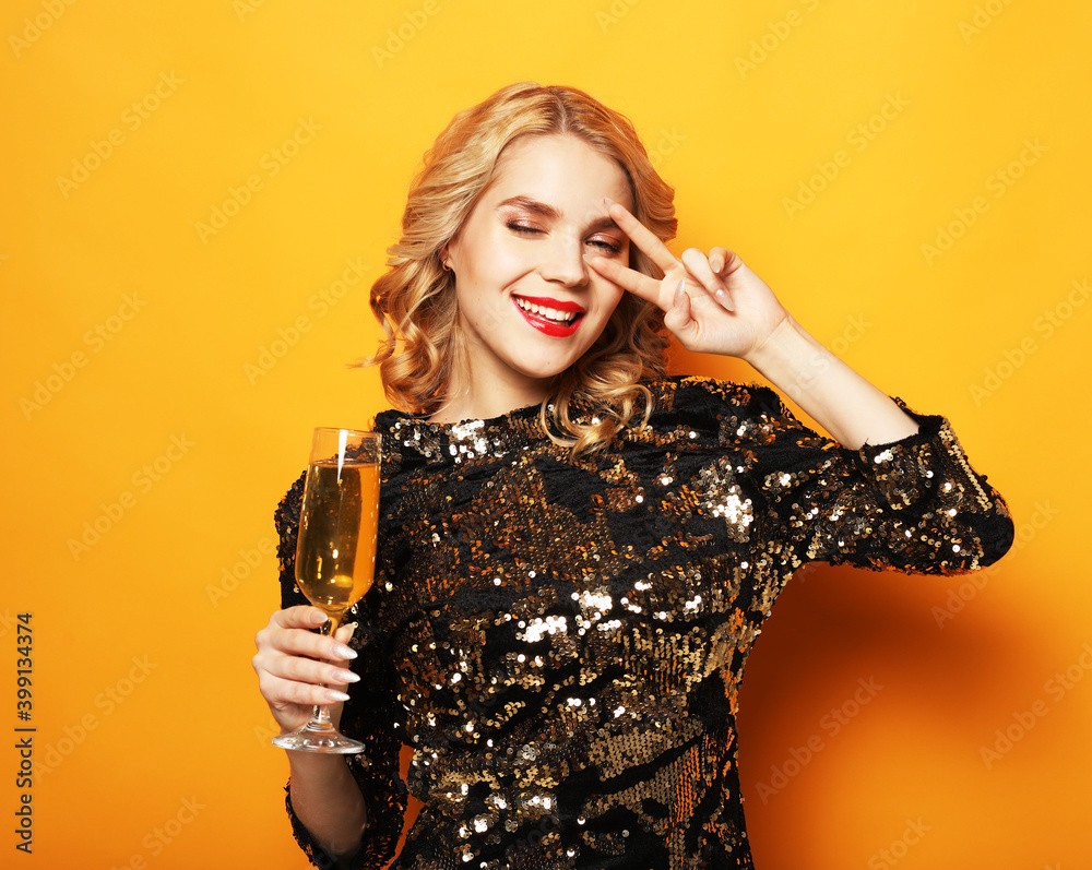 Portrait of smiling young woman wearing evening dress showing victory sign near eye . Holiday and celebrate concept. Portrait of smiling young woman wearing evening dress showing victory sign near eye . Holiday and celebrate concept.