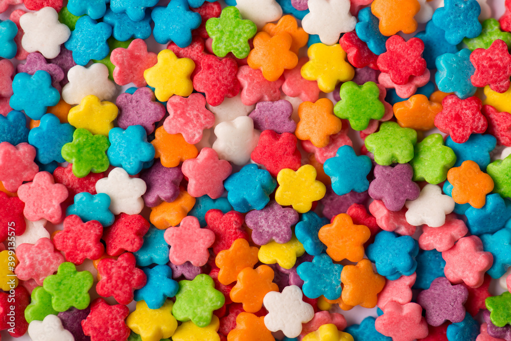 Close-up top view photo of small little shiny colorful mini flowers sugar icing textured background Close-up top view photo of small little shiny colorful mini flowers sugar icing textured background