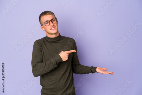 Young caucasian handsome man excited holding a copy space on palm. © Asier