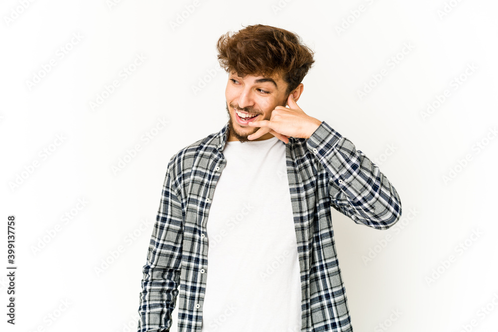 Young arab man on white background showing a mobile phone call gesture with fingers.