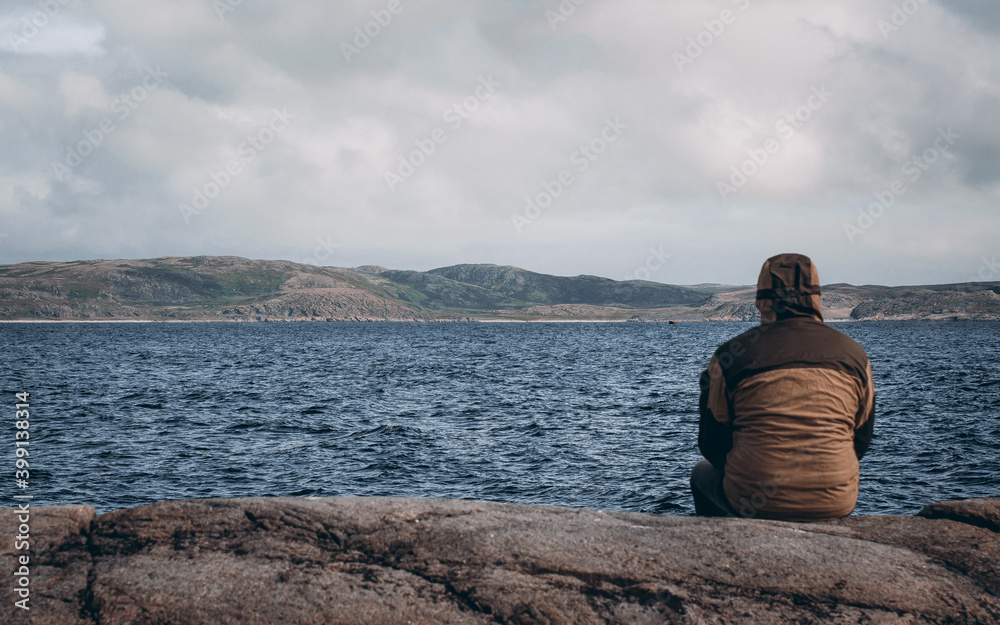 A man sits on a stone and thinks about the pollution of the world's oceans