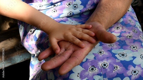 Small kid hand atop opened hand palm of old lady. Great grandmother holds little hand of her great grandchild. Diverse hands of 4 year old child and 80 year old woman of multi generation family