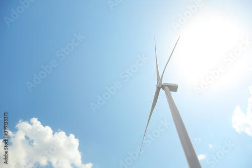 Modern wind turbine against blue sky, low angle view. Energy efficiency © New Africa