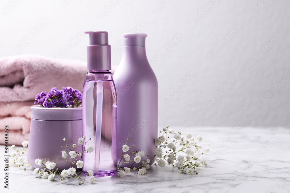 Set of hair cosmetic products and flowers on white marble table. Space for text Set of hair cosmetic products and flowers on white marble table. Space for text