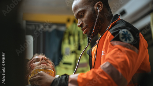 фотографія Black African American EMS Professional Paramedic Providing Medical Help to Injured Patient on the Way to Hospital