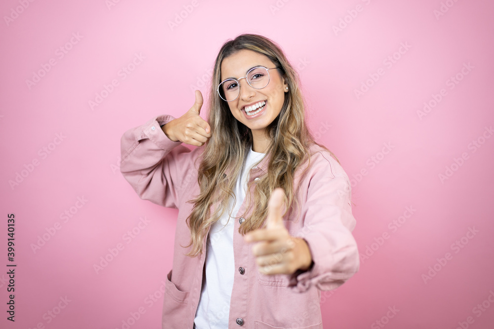 Young beautiful blonde woman with long hair standing over pink background pointing to you and the camera with fingers, smiling positive and cheerful Young beautiful blonde woman with long hair standing over pink background pointing to you and the camera with fingers, smiling positive and cheerful