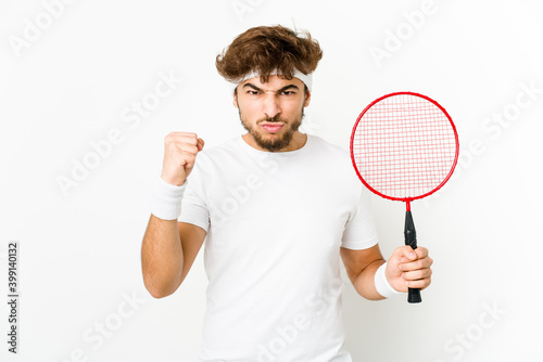 Young indian man playing badminton showing fist to camera, aggressive facial expression.