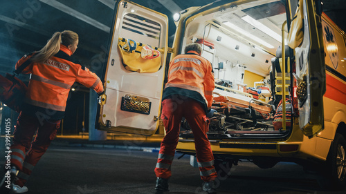 Team of EMS Paramedics Quickly Take Out a Stretcher from Ambulance Vehicle and Help an Injured Person. Emergency Care Assistants Arrived on the Scene of a Traffic Accident on a Street at Night.
