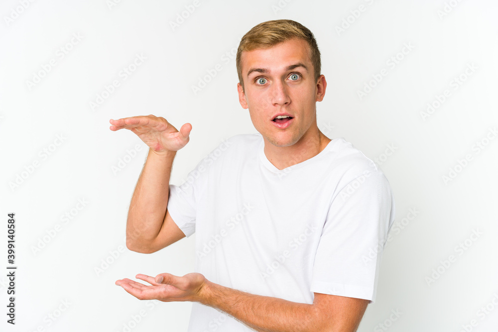 Young caucasian handsome man shocked and amazed holding a copy space between hands. Young caucasian handsome man shocked and amazed holding a copy space between hands.