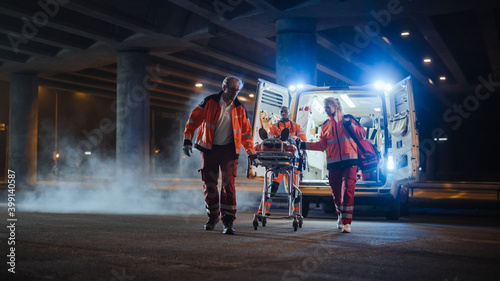 Team of EMS Paramedics React Quick to Bring Injured Patient to Healthcare Hospital and Get Him Out of Ambulance on a Stretcher. Emergency Care Assistants Help Young Man to Stay Alive After Accident.