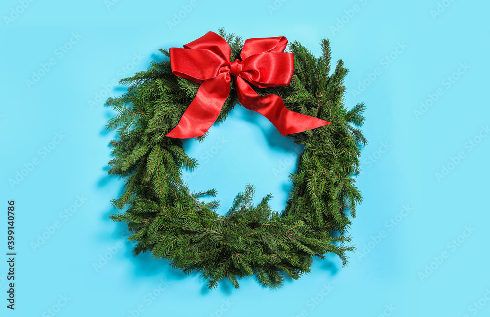 Christmas wreath made of fir branches with red bow on light blue background Christmas wreath made of fir branches with red bow on light blue background