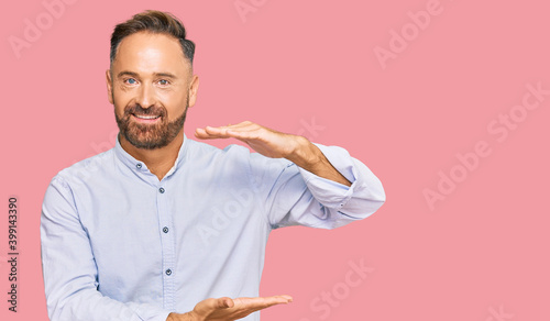 Handsome middle age man wearing business shirt gesturing with hands showing big and large size sign, measure symbol. smiling looking at the camera. measuring concept.