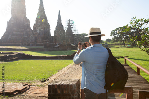 Travel and tourism. Men traveling in Thailand. Male travelling in ruins of Ancient Ayutthaya. Young caucasian man walk on a wooden bridge in the morning at temple in old city of Ayutthaya in Thailand.