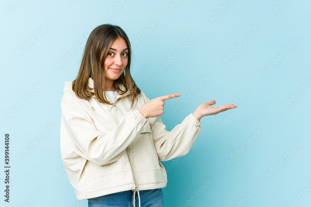 Young caucasian woman excited holding a copy space on palm. Young caucasian woman excited holding a copy space on palm.