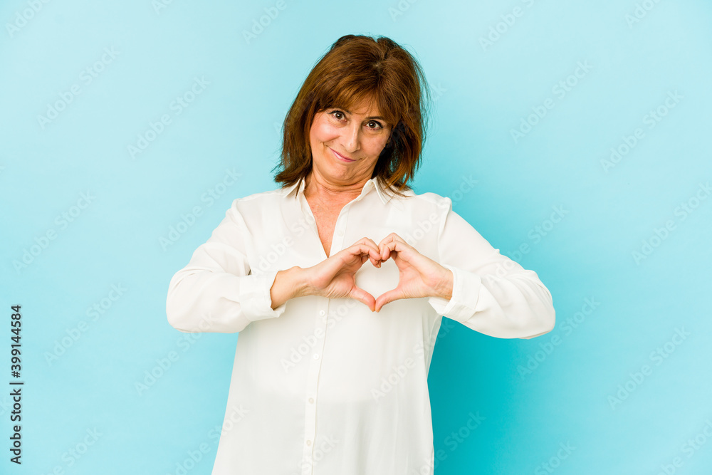 Senior caucasian woman isolated smiling and showing a heart shape with hands.