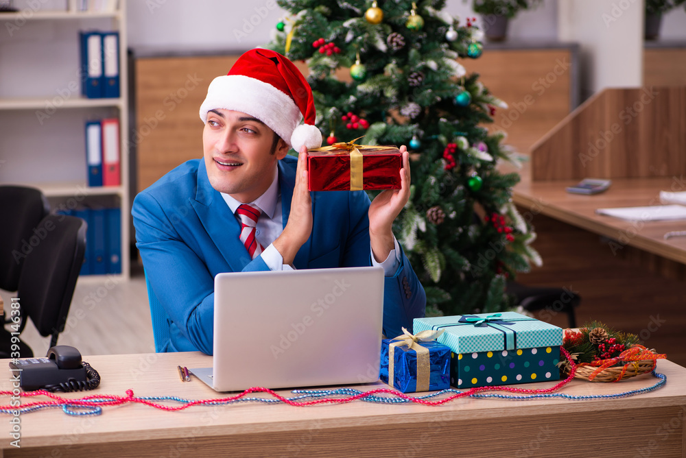 Young male employee celebrating Christmas at workplace Young male employee celebrating Christmas at workplace