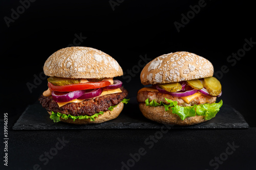 Two Burgers with meat on black plate at black background