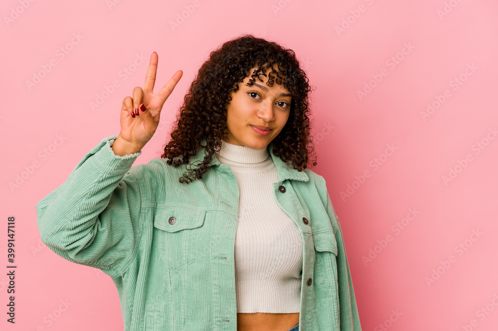 Young african american afro woman isolated joyful and carefree showing a peace symbol with fingers. Young african american afro woman isolated joyful and carefree showing a peace symbol with fingers.