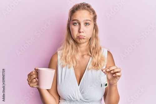 Young blonde girl holding cup of tea depressed and worry for distress  crying angry and afraid. sad expression.