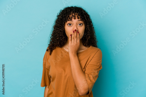 Young african american afro woman isolated shocked, covering mouth with hands, anxious to discover something new. © Asier