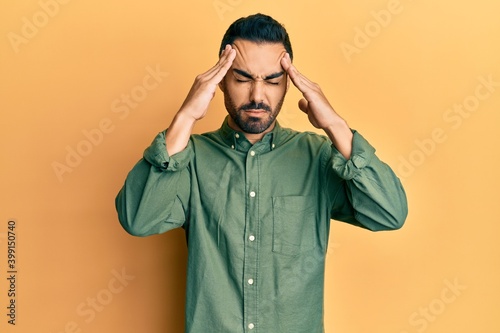 Young hispanic man wearing casual clothes with hand on head, headache because stress. suffering migraine.
