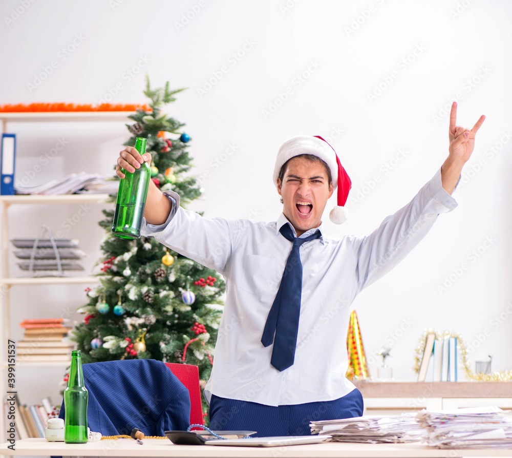 Young handsome employee celebrating Christmas at workplace Young handsome employee celebrating Christmas at workplace