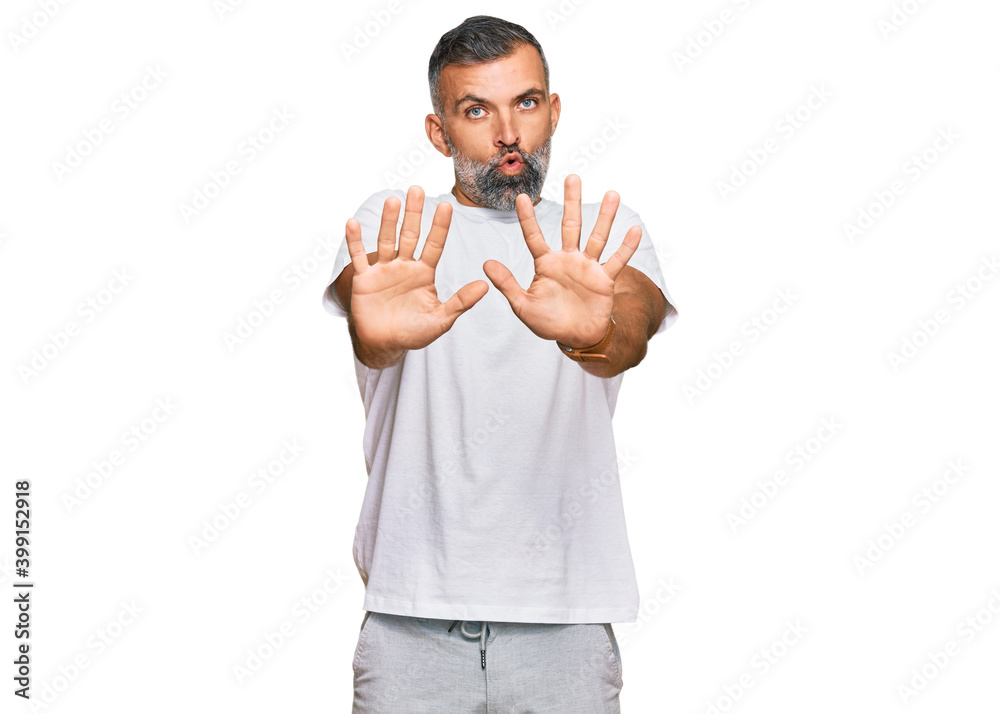 Middle age handsome man wearing casual white tshirt moving away hands palms showing refusal and denial with afraid and disgusting expression. stop and forbidden. Middle age handsome man wearing casual white tshirt moving away hands palms showing refusal and denial with afraid and disgusting expression. stop and forbidden.
