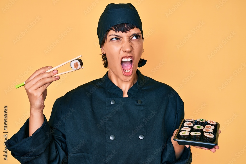 Beautiful brunettte woman chef holding sushi using chopsticks angry and mad screaming frustrated and furious, shouting with anger. rage and aggressive concept. Beautiful brunettte woman chef holding sushi using chopsticks angry and mad screaming frustrated and furious, shouting with anger. rage and aggressive concept.