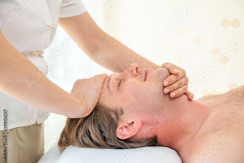 Caucasian man lying on spa bed get facial massage treatment with aroma essential oil skincare from professional female massage therapist at beauty salon. Wellness body massage and face spa concept