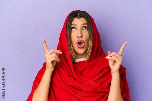 Young indian woman wearing a hijab isolated pointing upside with opened mouth.
