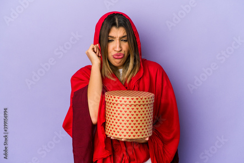 Young indian woman wearing a hijab holding a valentines day gift isolated covering ears with hands.