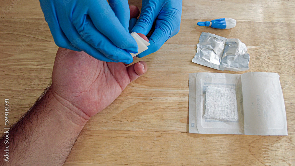 Foto de A medical personnel wearing gloves is wiping the finger tip of