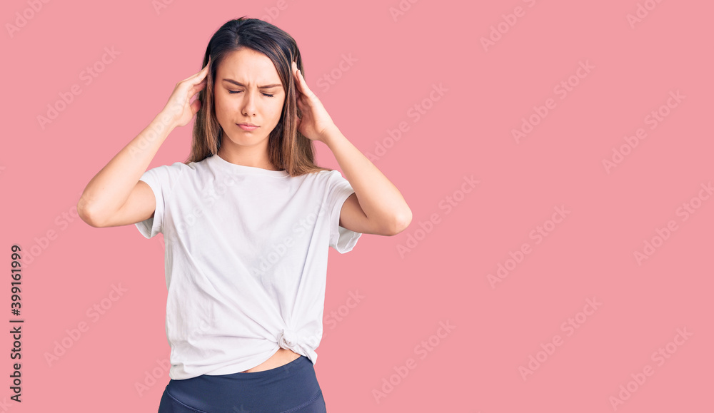 Young beautiful girl wearing casual t shirt suffering from headache desperate and stressed because pain and migraine. hands on head.