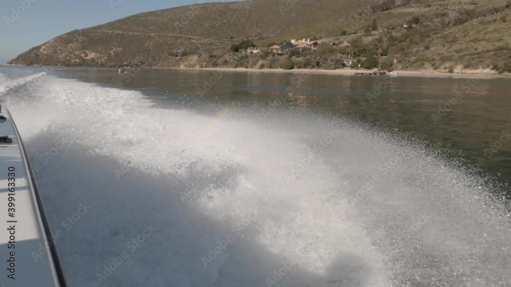 Subtle rainbow and tight turn splashes water from fast speed boat wake