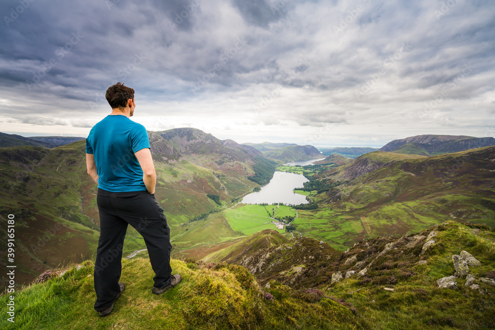 Man standing on top of Haystacks peak looking at Buttermere lake in Lake District. England
