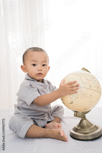 Portrait happy of a adorable little boy playing globe in bedroom
