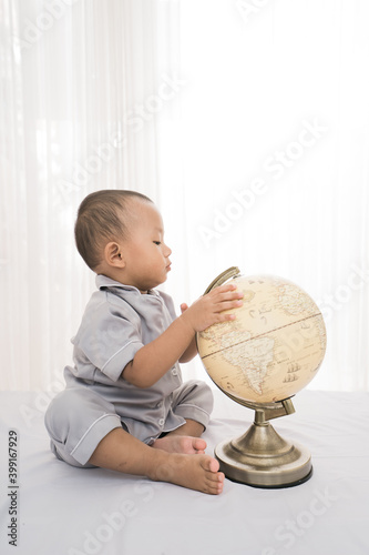 Portrait happy of a adorable little boy playing globe in bedroom