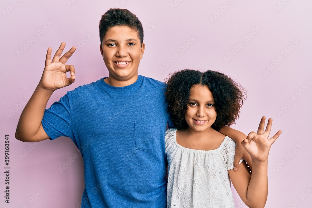 Young hispanic family of brother and sister wearing casual clothes together smiling positive doing ok sign with hand and fingers. successful expression. Young hispanic family of brother and sister wearing casual clothes together smiling positive doing ok sign with hand and fingers. successful expression.