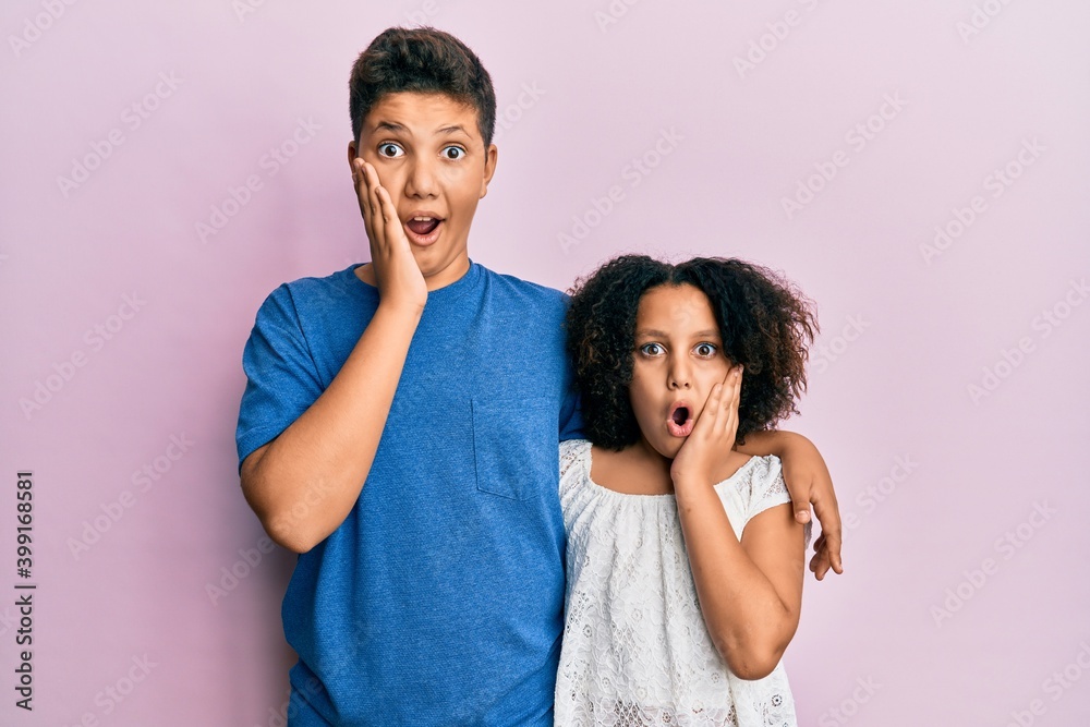 Naklejka premium Young hispanic family of brother and sister wearing casual clothes together afraid and shocked, surprise and amazed expression with hands on face