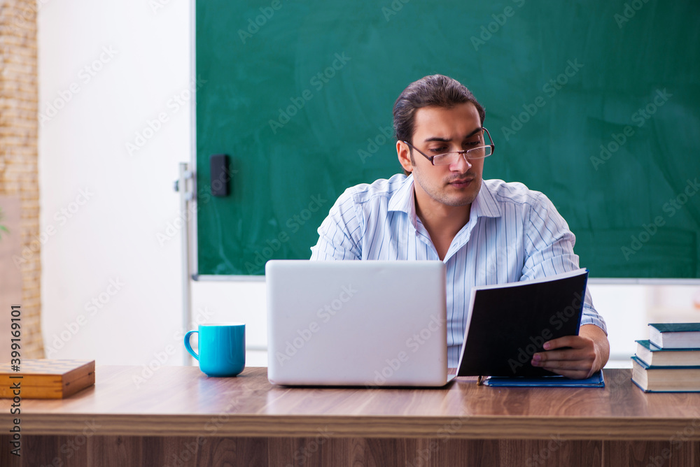 Young male teacher in front of blackboard Young male teacher in front of blackboard