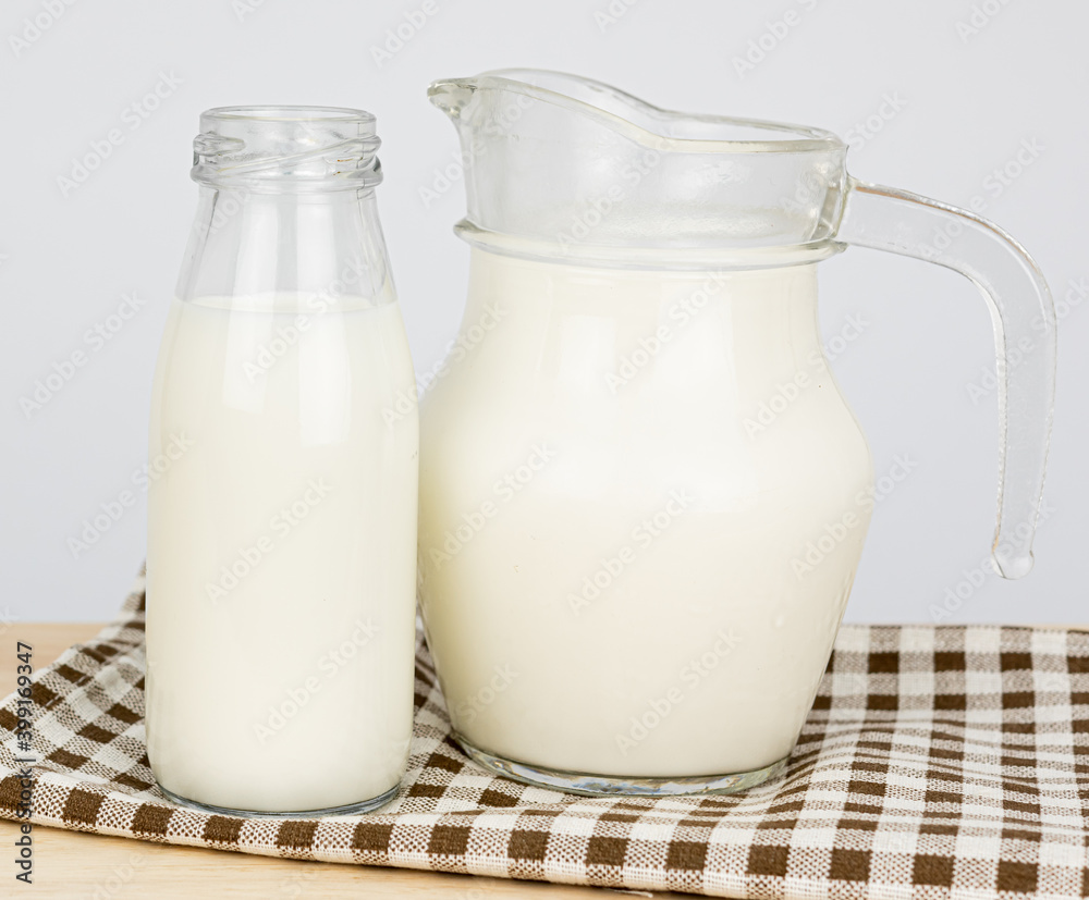 Bottles with fresh milk on a wooden table..Jug of fresh milk and glass on a gray background, .Milk consumption nutritious, and healthy dairy products concept. Bottles with fresh milk on a wooden table..Jug of fresh milk and glass on a gray background, .Milk consumption nutritious, and healthy dairy products concept.