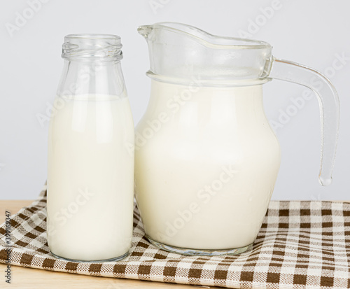 Bottles with fresh milk on a wooden table..Jug of fresh milk and glass on a gray background, .Milk consumption nutritious, and healthy dairy products concept.