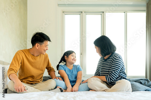 asian Senior grandparents couple laying with grandchildren pretty female child on bed in bedroom,happy family play together in the bed