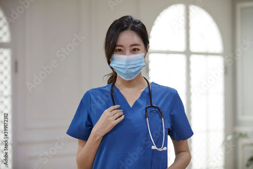 마스크를 쓰고 파란색 수술복을 입은 여성 의사