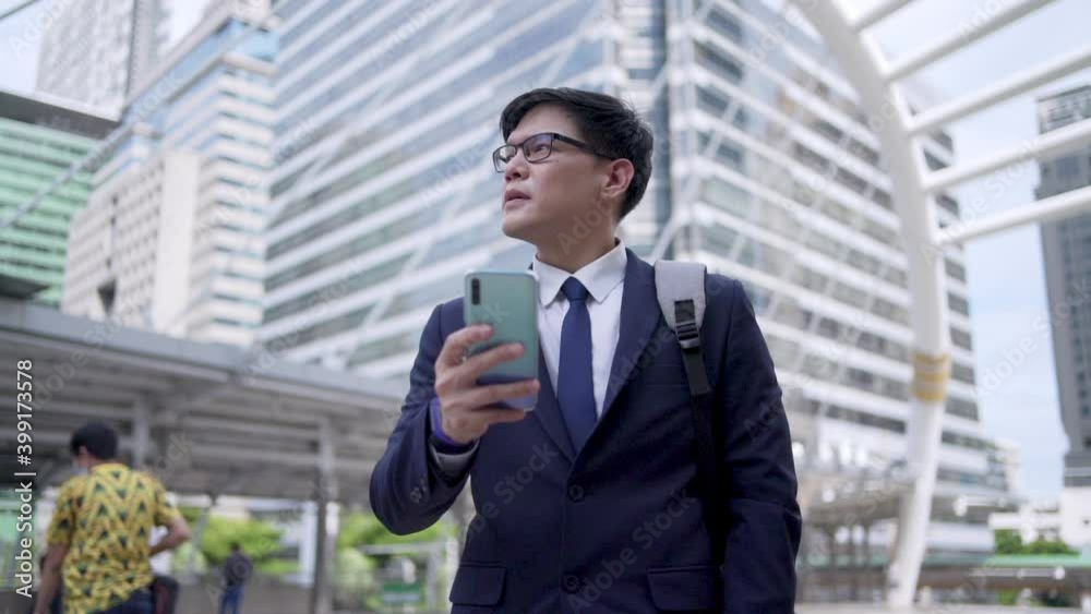 Confident Asian business man office worker in suit walking in city with texting online message on smartphone. Businessman using mobile phone for online working corporate business in office district Confident Asian business man office worker in suit walking in city with texting online message on smartphone. Businessman using mobile phone for online working corporate business in office district