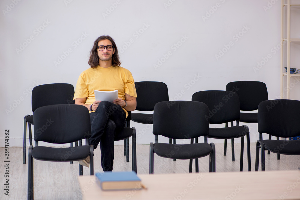 Young male student waiting for teacher in the classroom Young male student waiting for teacher in the classroom