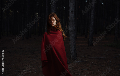 woman in nature covered herself with a red blanket in the forest travel tourism